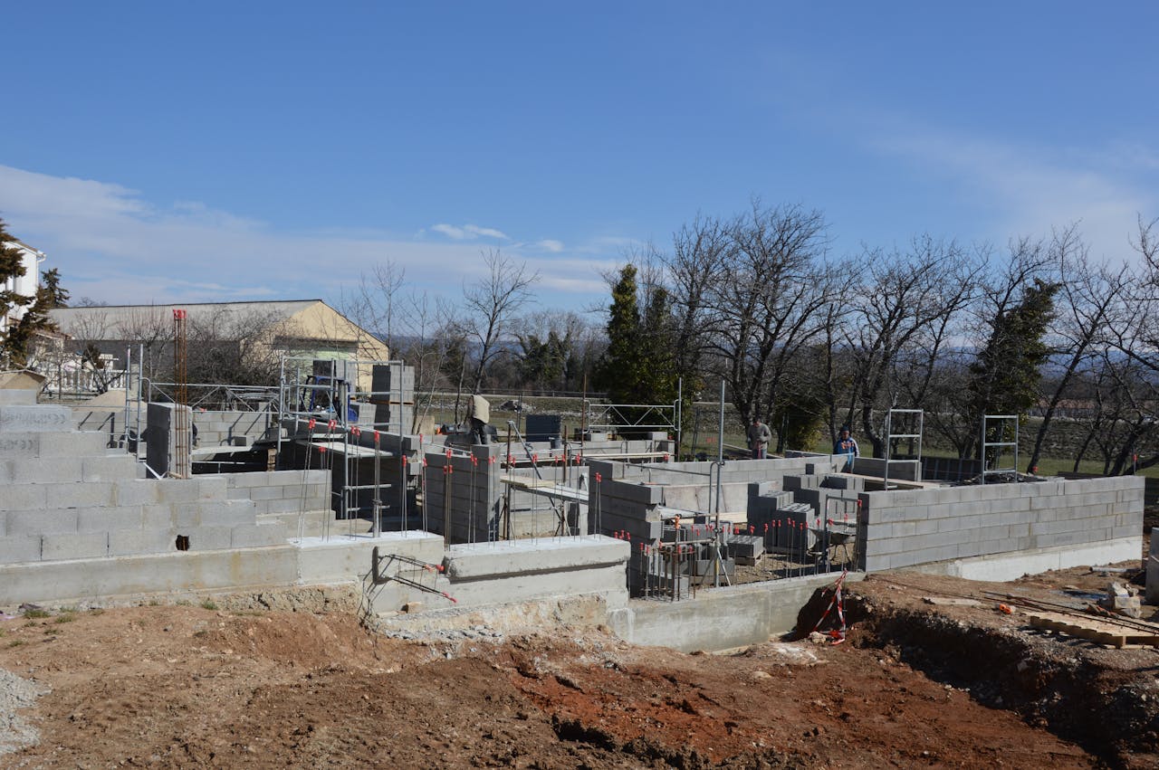 Outdoor construction site showing cinder block walls and scaffolding under a clear sky.